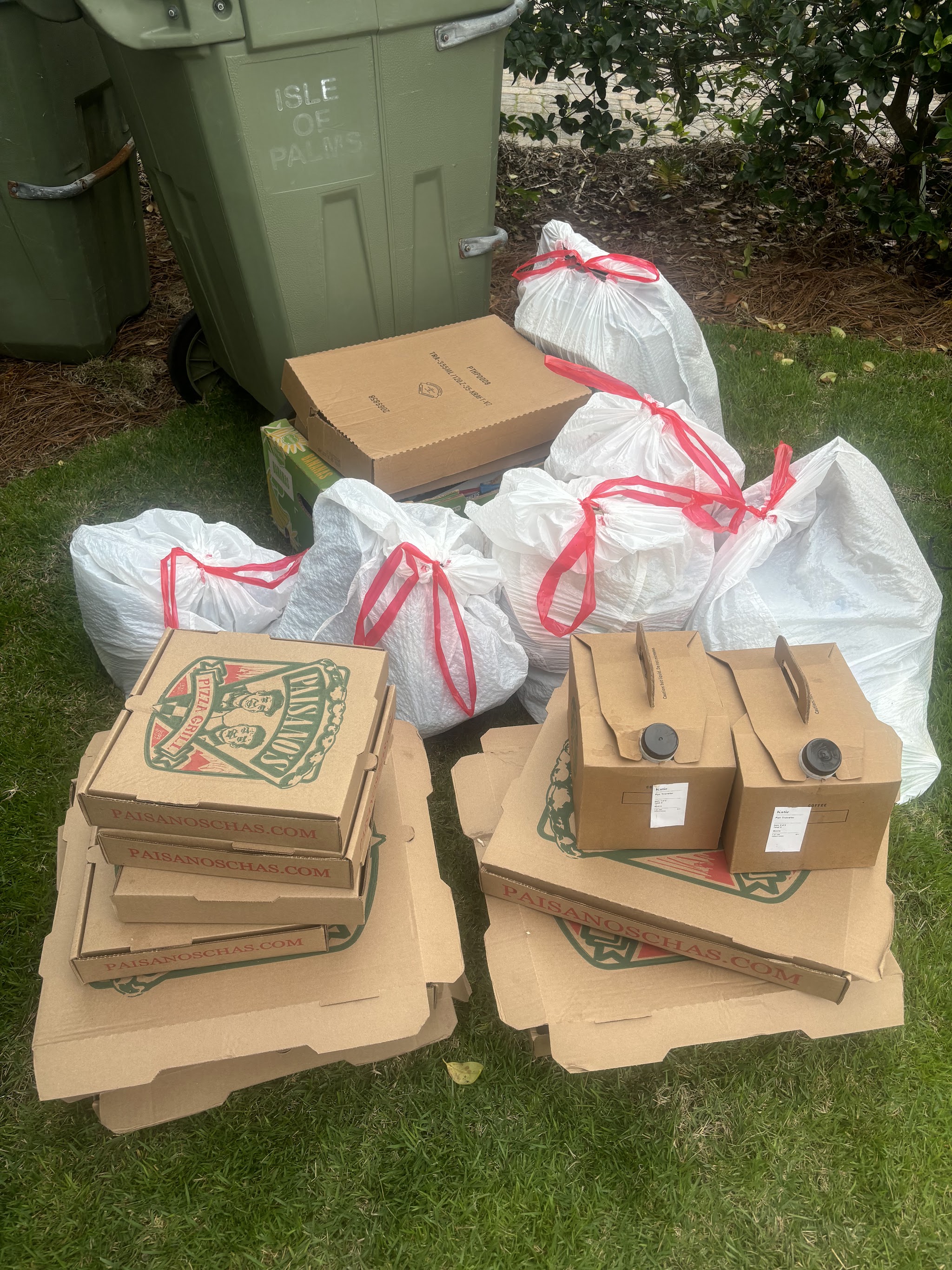 Trash bags and pizza boxes on a lawn